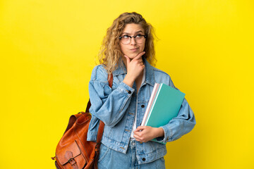 Wall Mural - Young student caucasian woman isolated on yellow background having doubts