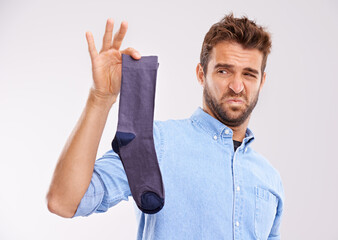 Poster - This isnt going anywhere near to my feet. Studio shot of a handsome young man holding an unpleasant smelling sock against a gray background.