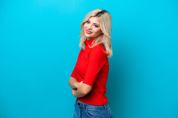 Young Russian woman isolated on blue background with arms crossed and looking forward