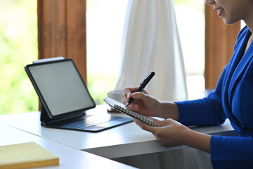 Poster - Close up businesswoman sitting in the office working on a blank white screen tablet on the table, for business, finance and technology concept.