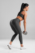 © nikolas_jkd - Fitness woman doing deadlift exercise for glutes on gray background. Athletic girl working out