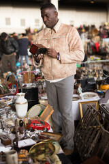 Wall Mural - ordinary Afro-American guy considers things sacond hands on flea market