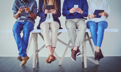 Poster - Byod and dont get bored while you wait. Studio shot of a group of unrecognizable businesspeople using wireless technology while sitting in line against a grey background.