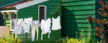 Typical Example Of Dutch Culture. White Laundry Hanging Outside In Front Of Wooden Green House In The Netherlands