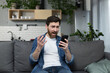 © Liubomir - The man himself at home, shocked and disappointed, looks at the phone, sitting on the couch