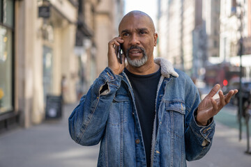 Sticker - Mature black man in city talking on cellphone on street