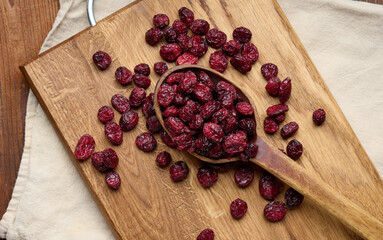 Wall Mural - bunch of dried cranberries in a wooden spoon on a brown table. Delicious berry, top view