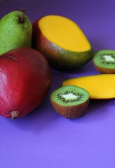 Wall Mural - fresh fruit, juicy mango, kiwi cut in half, large pear, colors, purple background, vitamins, sweet nature