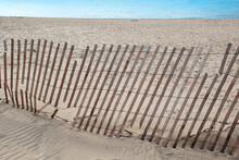 Broken Snow Fence In Beach Sand With Blue Lake Water