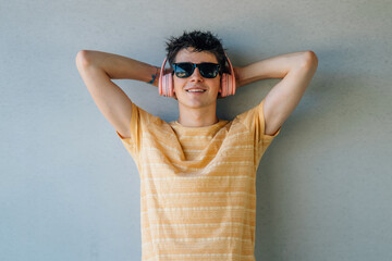 Wall Mural - young man with sunglasses and headphones relaxing on the wall