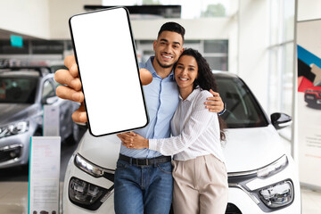 Happy middle eastern couple showing cell phone, buying new auto