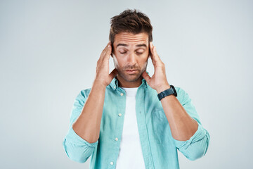 Poster - I cant concentrate properly. Studio shot of a young man with an uncomfortable facial expression due to a headache while standing against a grey background.