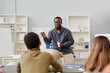 © Seventyfour - Front view portrait of African American science teacher explaining chemistry to group of children in school class and holding molecule models