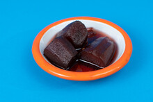 Close-up Shot Of Eggplant Jam And White Plate With Orange Rim On Isolated Area, Blue Background With Selective Focus From Opposite Or Side Angle.