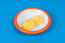 Close-up Shot Of White Plate With Butter And Orange Rim On Isolated Area, Blue Background With Selective Focus From Opposite Or Side Angle.