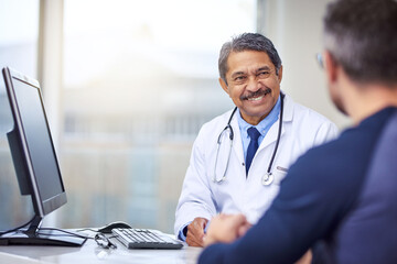 Poster - He gives all the right medical advice youll ever need. Shot of a cheerful mature male doctor seated at his desk while consulting a patient inside a hospital during the day.