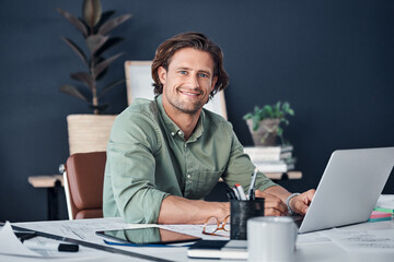 Wall Mural - Im in full work mode. Portrait of a handsome young businessman working on a laptop in his office.