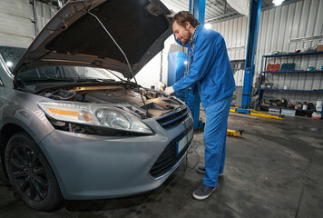 Wall Mural - Mechanic inspecting engine compartment in service center