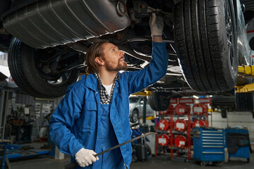 Wall Mural - Adult car mechanic repairing car at service station