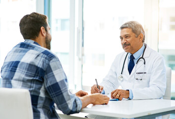 Wall Mural - Rest assured your results are looking good. Shot of a confident mature male doctor consulting with a patient inside of his office during the day.