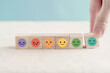 Hand choosing happy smile face wooden block, good feedback rating and positive customer review, mental health assessment, child wellness,world mental health day, think positive, compliment day concept