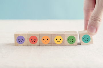 Wall Mural - Hand choosing happy smile face wooden block, good feedback rating and positive customer review, mental health assessment, child wellness,world mental health day, think positive, compliment day concept