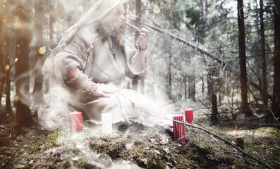 Fairy magician. A sorcerer with a glass sphere, a magical spell and a ritual. Elder with a staff and a cross in the forest. Black and white magic. A spell in an old book.