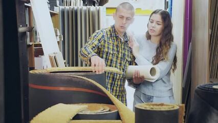 Wall Mural -  Glad positive couple, husband and wife, looking at flooring samples in a building hypermarket