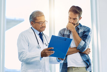 Canvas Print - Theres a few things you have to focus on here. Shot of a confident mature male doctor showing test results to a patient inside of a hospital during the day.