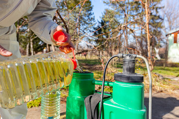 Gardener is blending substance with water in proper scale for sprinkles fruit trees