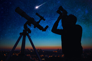 Wall Mural - silhouette of a man while watching starry skies with astronomy telescope and binoculars.