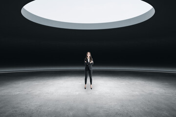 Canvas Print - Thoughtful young european businesswoman standing in abstract space ship interior with spotlight from above. Presentation concept.