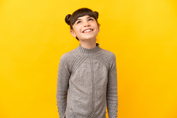 Little caucasian girl isolated on yellow background thinking an idea while looking up