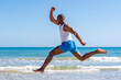 © Westend61 - Smiling athlete jumping in front of water at beach on sunny day