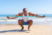 Smiling Sportsperson With Resistance Band Crouching At Beach