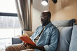 © Westend61 - Young man reading novel on sofa at home