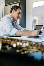 Saxophonist Writing Musical Notes By Tablet PC On Table At Home