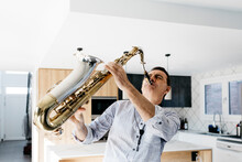 Passionate Saxophonist Practicing Saxophone In Kitchen At Home