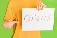 Woman Pointing Vegan Food Placard Against Green Background