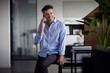 © Westend61 - Happy businessman talking on smart phone sitting on desk in office
