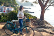 © Westend61 - Woman walking with bicycle looking at the coast