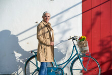 Woman With Bicycle Standing In Front Of Wall