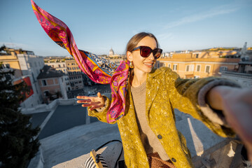 Wall Mural - Woman enjoying beautiful morning cityscape of Rome, taking selfie photo, while sitting on the top of famous Spanish steps. Concept of happy vacations in Rome