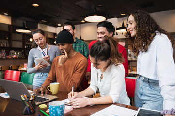 Multiracial mixed group of young people sitting at desk. Co-workers or teamwork of university students working together.