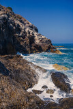 Fototapeta Morze - Wonderful views of the blue Mediterranean Sea. Sunny rocks, waves with foam and splashing water. The wave crashes into the rocks on the shore