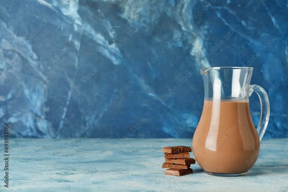 Jug of delicious chocolate milk on color background