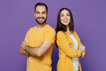 Wall Mural - Young smiling fun cool happy cheerful couple two friends family man woman together in yellow casual clothes look camera hold hands crossed folded isolated on plain violet background studio portrait