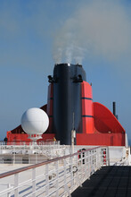 Red And Black Funnel Of Classic Ocean Liner Cruise Ship Cunard Queen Mary 2 QM2 Against Deep Blue Sky During Cruise In Summer	
