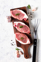 a pieces of raw fresh pork with salt on a cutting board on light background. meat with spices