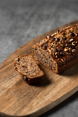 Canvas Print - Vertical shot of a loaf of banana bread on a wooden cutting board on the table